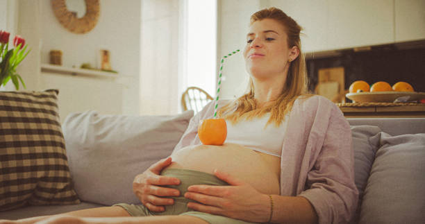 In a grocery store, a pregnant woman stands by a fruit stand, surrounded by various natural foods. She is in a public space where the local market offers whole foods for trade Pregnant woman buying organic vegetables and fruits at Mexican style farmers market