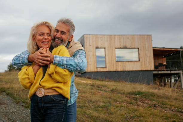 Couple Facing Ghosted House Drawing and Photo Over Green Landscape.