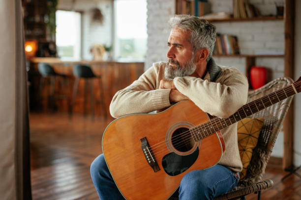 istock Pensive man with acoustic guitar at home 2159298132
