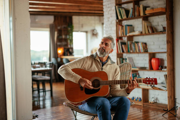 istock Mature man playing acoustic guitar at home 2159298139