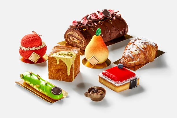 Fruit shaped pastries, cheesecake with berry jelly, pistachio eclair, chocolate roll, cubic and crescent croissants on white