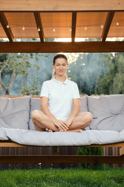 istock Cheerful woman sits cross-legged on a swing 2159305020