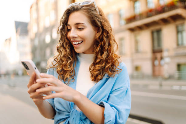 istock Smiling young woman walking around old street and using smartphone. 2159305975