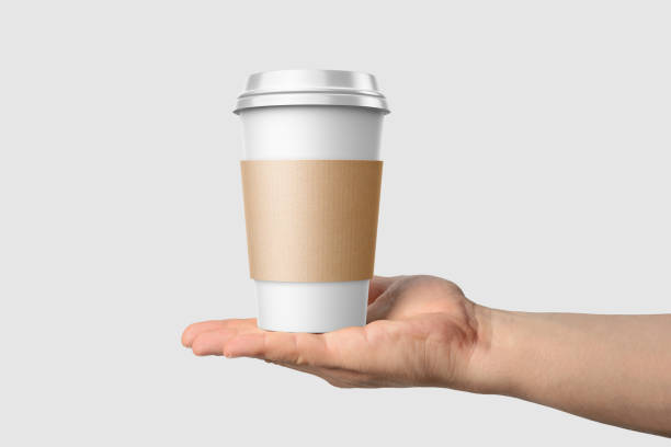 istock Paper coffee cup with sleeve in a hand mockup template, isolated on light grey background. 2159307594