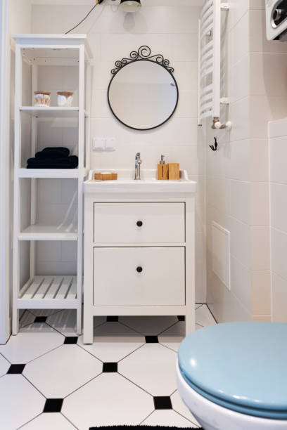 Home interior with ceramic bathroom sink and white tile on the wall with circle mirror. Rustic bathroom in indoors architecture and cosy design. Vertical