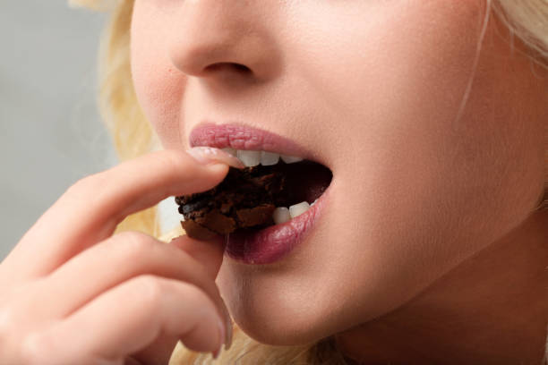 istock Blonde woman eating chocolate cookie showing gluttony 2159310467