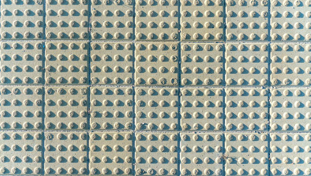Tactile paving tiles with raised bumps on sidewalk. Surface texture designed for visually impaired pedestrians