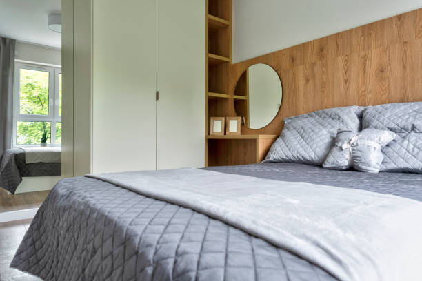 istock Modern and comfortable bedroom with double bed with grey pillow and blanket. Home interior with wood on the wall. 2159315078