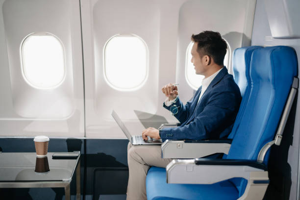 istock Young Asian executive excels in first class, multitasking with digital tablet, laptop and smartphone. Travel in style, 2159315196
