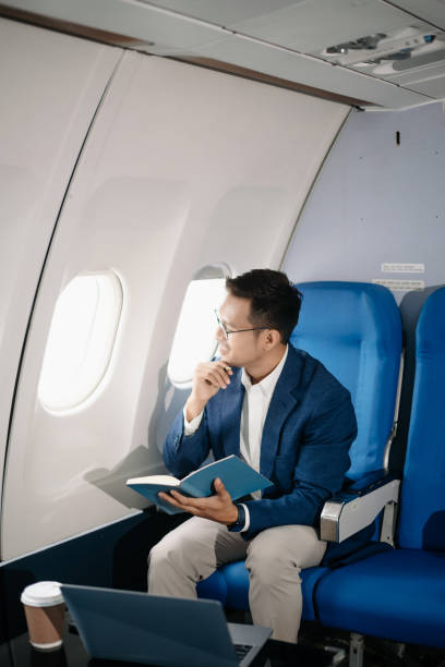 istock Young Asian executive excels in first class, multitasking with digital tablet, laptop and smartphone. Travel in style, 2159315208