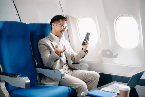 istock Young Asian executive excels in first class, multitasking with digital tablet, laptop and smartphone. Travel in style, 2159315247