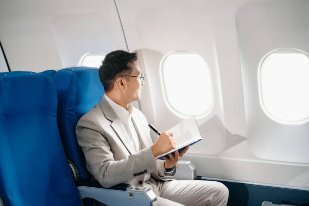 istock Young Asian executive excels in first class, multitasking with digital tablet, laptop and smartphone. Travel in style, 2159315271