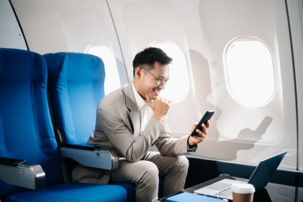 istock Young Asian executive excels in first class, multitasking with digital tablet, laptop and smartphone. Travel in style, 2159315280