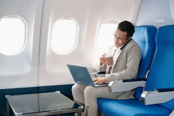istock Young Asian executive excels in first class, multitasking with digital tablet, laptop and smartphone. Travel in style, 2159315284