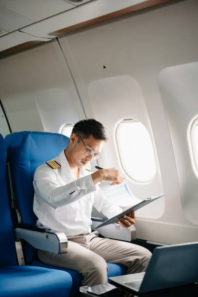istock Asian Confident male pilot in uniform leaning at the passenger seat while standing inside of the airplane flight cockpit during takeof 2159315335