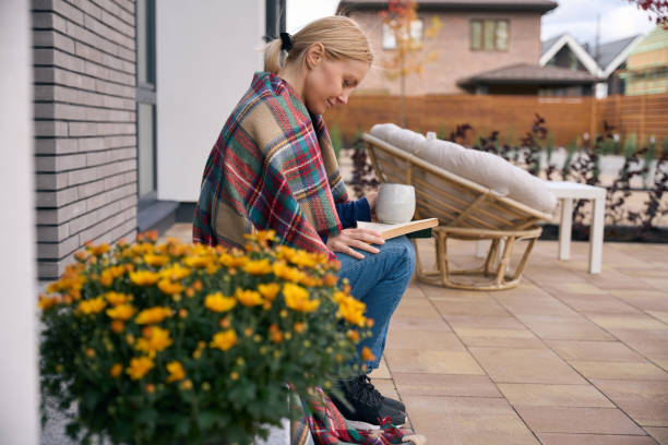 istock Woman sitting on doorstep when drinking coffee and reading book 2159315513