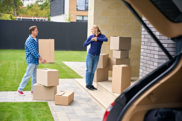 istock Joyful man carrying box to smiling lady standing on doorstep 2159315551