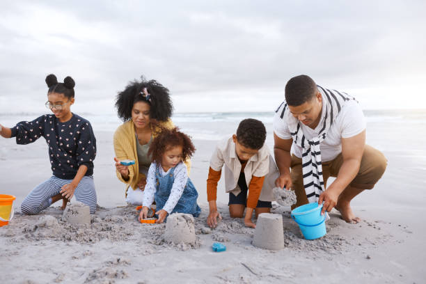 istock Happy parents playing with three children building sand castle on beach 2159318049
