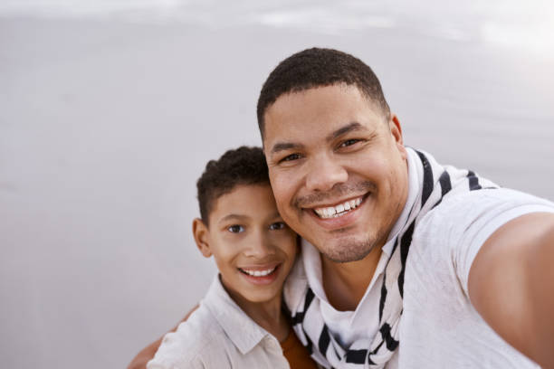 istock High angle view of father and son smiling happily at camera on beach 2159318074