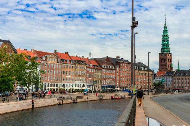 Copenhagen, Denmark - 16 June, 2024: people walking alongside the canal on a city street in downtown Copenhagen, Denmark.