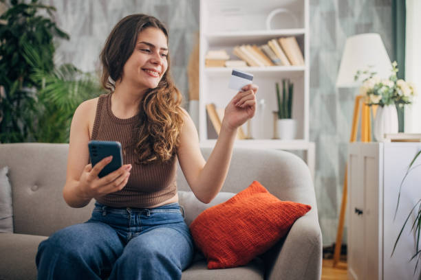 istock Joyful woman using credit card with phone 2159320867