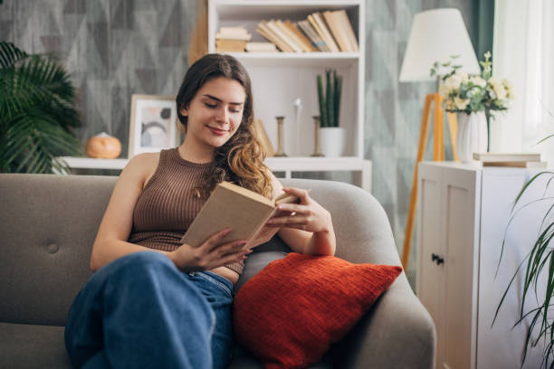 istock Woman reading a book on a cozy couch 2159321662