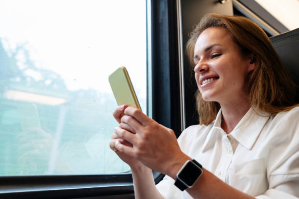 istock Brunette woman online messages using her smart phone while travelling by train. 2159323041