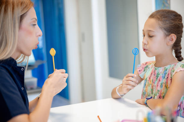 istock Female doctor and elementary age girl using special tool at speech therapy 2159323964