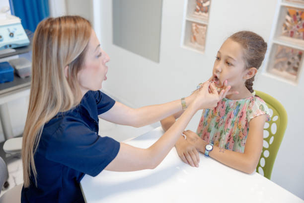 istock Female doctor using tool for speech therapy, girl at the appointment 2159324008