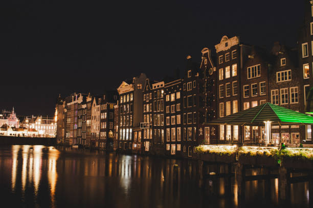 Illuminated buildings in the Damrak's Amsterdam canal at night