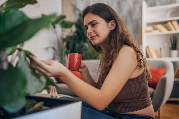 istock Thoughtful woman looking at her plant 2159325204