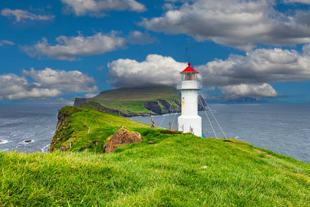 istock White lighthouse standing on green grass field 2159326731