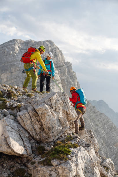 istock Group of mountain climbers helping eachother to the top 2159331527