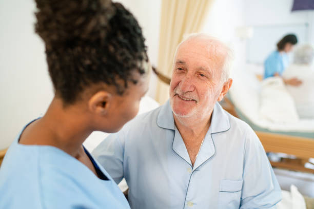 istock Elderly man patient being assisted by nurse in nursing home 2159332036