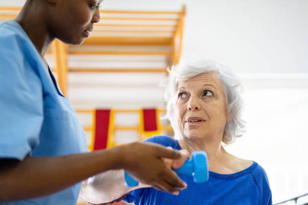 istock Therapist guides mature patient in strengthening exercise with dumbbell 2159332238