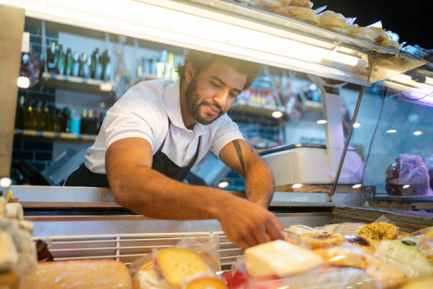 istock Young man arranging the cheese refrigerator display at a delicatessen 2159332690