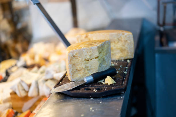 Traditional handmade cheese blocks on cutting board on grocery store counter. Close-up of fresh cheese on delicatessen counter.