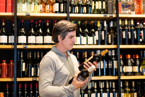 istock Mature man choosing a wine to purchase at wine store 2159332818
