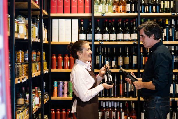 istock Friendly vintner suggesting a wine to mature man customer at wine store 2159332848