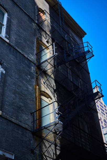 Urban Fire Escape Shadows on Brick Facade with Blue Sky Background