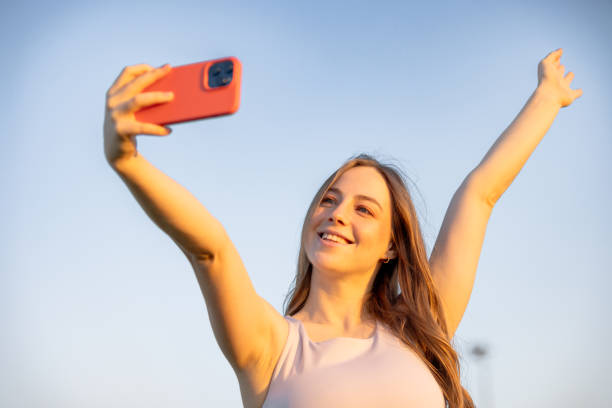 istock Beautiful young woman is taking selfie with blue sky background. 2159340967