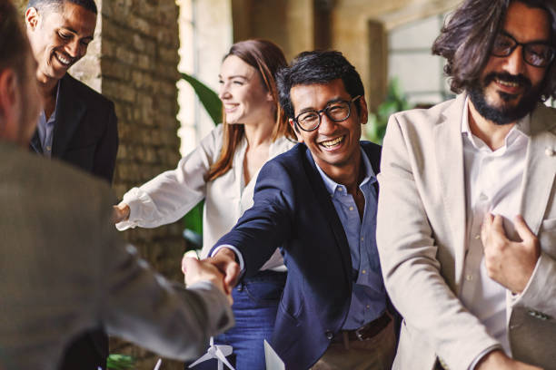 Multicultural Business Professionals Celebrating Success Group of diverse professionals celebrating with a handshake at a corporate event, embodying teamwork and achievement. event stock pictures, royalty-free photos & images