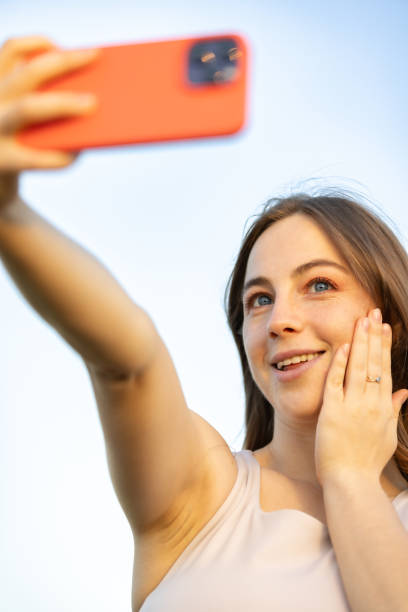 istock Beautiful young woman is taking selfie with blue sky background. 2159342319
