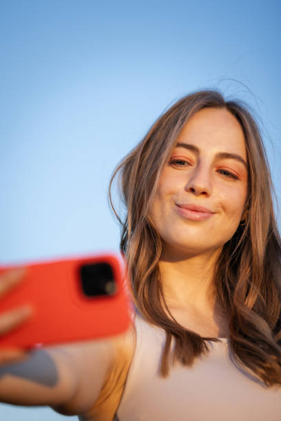 istock Beautiful young woman is taking selfie with blue sky background. 2159342433