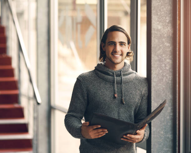 Man, university and smile in portrait for education, notebook for learning on campus. Male person, art student and creative portfolio at college, happiness for artistic knowledge with scholarship