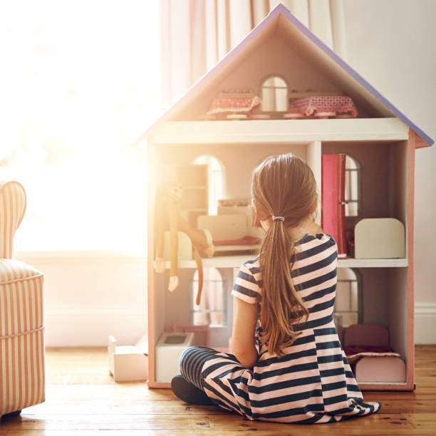 istock Dollhouse, home and child play with creative game, imagination and dream on floor for cognitive development. Kid back by tiny pink furniture for holiday toys, learning and story or fun activity alone 2159343017