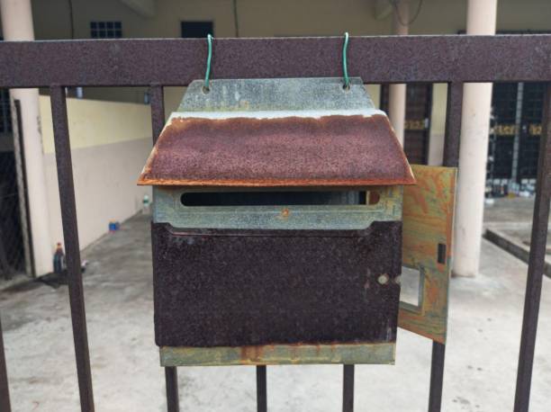 A rusted iron mailbox hung on the fence.