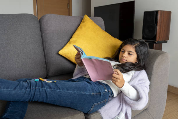 istock A young girl is reading a book on a couch 2159344724