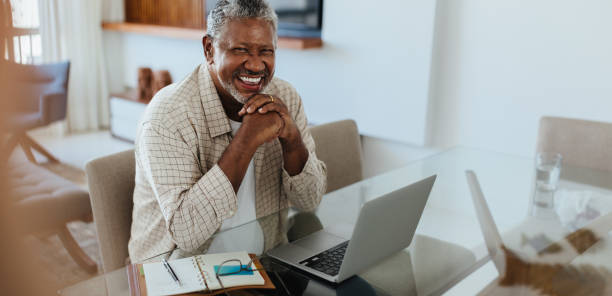 istock Happy older businessman smiling while working on laptop at home 2159347822