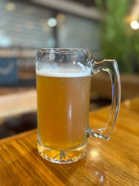 istock Tall glass pint filled with beer on a table, no people, with selective focus on beer mug and restaurant atmosphere blurred in background 2159349979